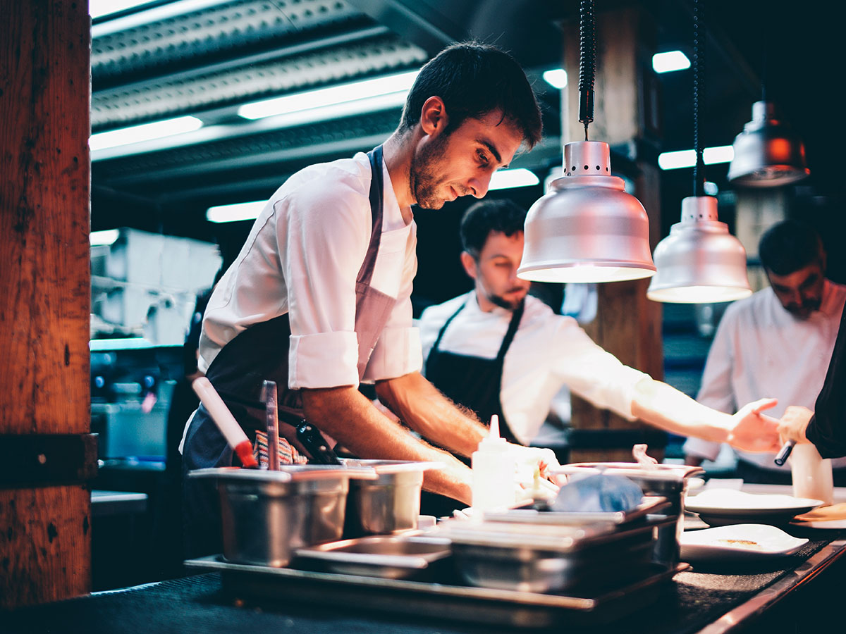 Koch in professioneller Restaurantküche unter Wärmelampen — Klimaanlage für Gastrobetriebe